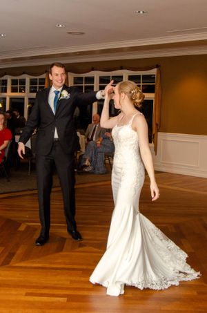 Couple dancing on hardwood floor during wedding reception.