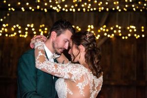 Wedding dance under romantic string lights with dark wooden backdrop.