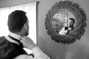 A reflection of formal attire adjustments in an ornate wall mirror.