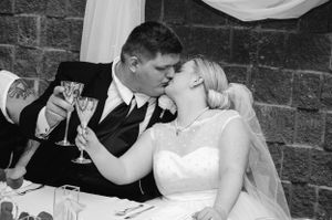 A black and white photo of newlyweds sharing an intimate moment during their wedding reception.