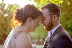 A romantic sunset portrait of newlyweds sharing an intimate forehead touch moment.