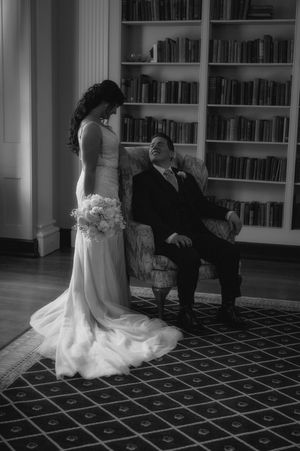 Elegant black and white portrait in library setting with formal attire.