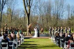 Outdoor wedding ceremony setup with white chairs on a lawn surrounded by bare winter trees.