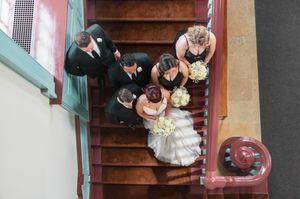Bird's eye view of a wedding party gathered on vintage wooden stairs.
