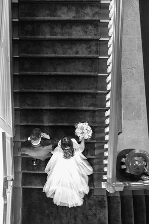 Overhead view of a bride descending a grand staircase with her flowing white dress trailing behind.
