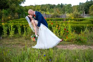A couple in wedding attire shares a romantic moment in a garden filled with colorful wildflowers and greenery.