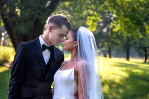 A romantic sunlit wedding portrait capturing a tender moment in a garden setting.