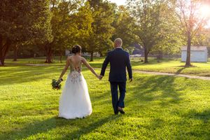 A couple walks hand in hand through a sunlit park during golden hour as sunbeams filter through the trees.