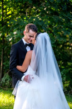 A romantic outdoor wedding moment captured between a couple under green foliage.