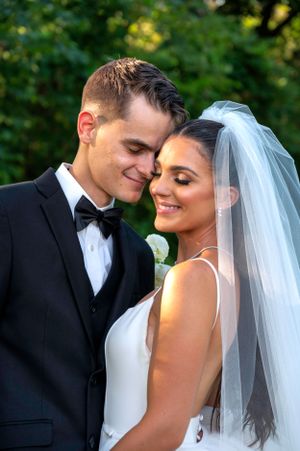 An intimate outdoor wedding portrait showing a tender moment between newlyweds.