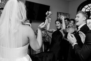 Wedding celebration moment with guests cheering and raising glasses during a reception.