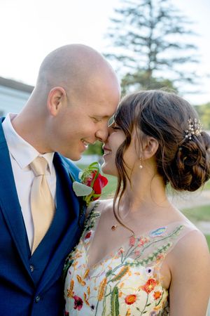 Romantic wedding couple in intimate close-up shots, with bride wearing floral dress against outdoor garden setting.