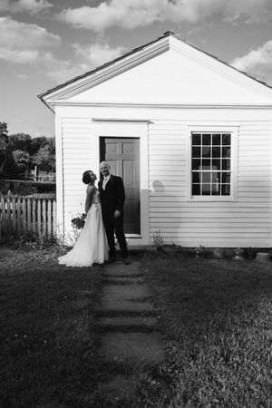 Black and white series showing newlyweds walking outside white farmhouse building in sequence.