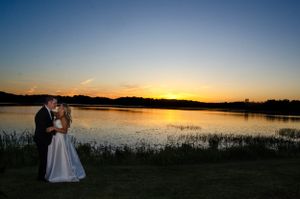 Silhouettes of a couple against a dramatic sunset over a lake.