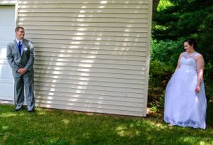 Creative wedding photo with couple standing on opposite sides of white building corner.