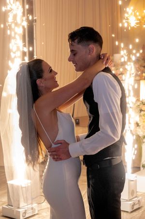 A couple shares their first dance with sparklers creating a magical backdrop at their wedding reception.