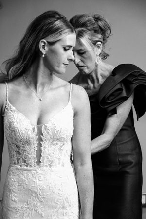 An intimate black and white portrait capturing a tender moment between two women in formal attire.