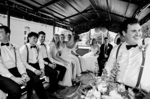 Black and white photo of wedding party members sitting in a covered outdoor venue.