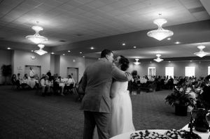 Black and white photo of a couple sharing their first dance in a reception hall.