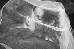 Intimate black and white portrait through delicate wedding veil.