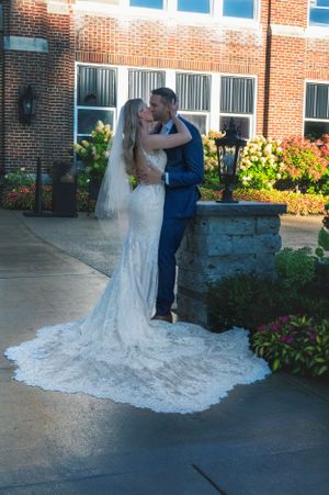A wedding couple sharing an intimate moment against a brick building backdrop.