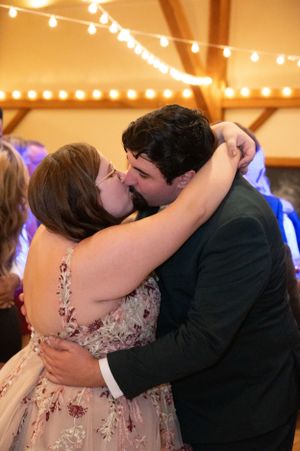 Couple sharing romantic moment under warm string lights at wedding reception.