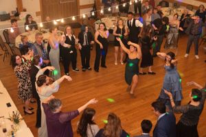 Wedding guests dancing together on wooden dance floor under string lights.