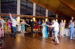 People dancing together in formal wear at an indoor reception venue with wooden floors.