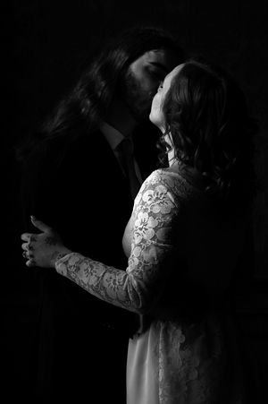 A romantic black and white portrait of a couple in an intimate embrace, with the woman wearing a lace dress.