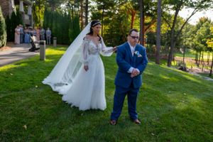 First look for wedding takes place on a scenic grassy lawn overlooking trees and gardens.