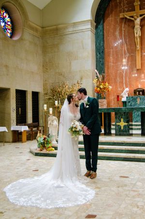 Interior of a church with stained glass windows and religious artifacts during a wedding ceremony.