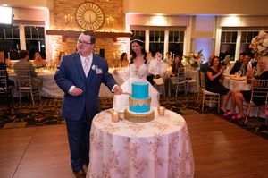 Wedding reception venue with elegant table settings and a three-tiered blue and white cake.