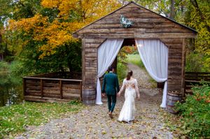 A rustic wooden barn entrance decorated with white flowing curtains during autumn.