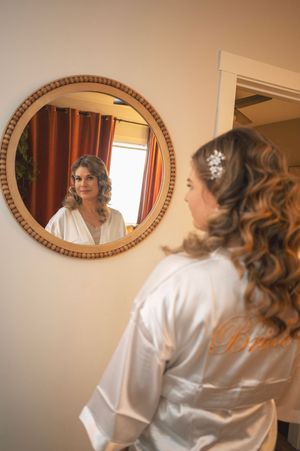 A series of oval mirrors reflects someone in a white robe getting ready in what appears to be a dressing room.