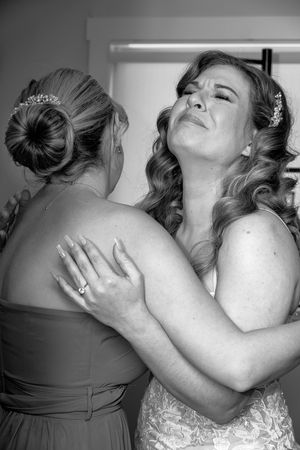 Two people in formal attire share an emotional embrace at a special event.