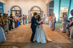 Bride and groom share first kiss during sparkler exit at elegant wedding venue with guests lining the aisle.