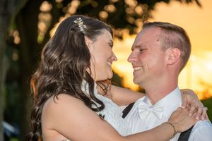 Bride and groom share a romantic moment at sunset, smiling at each other during their outdoor wedding celebration.