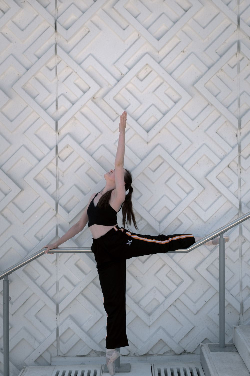 Danseuse classique en équilibre devant une façade aux motifs géométriques à Lyon.