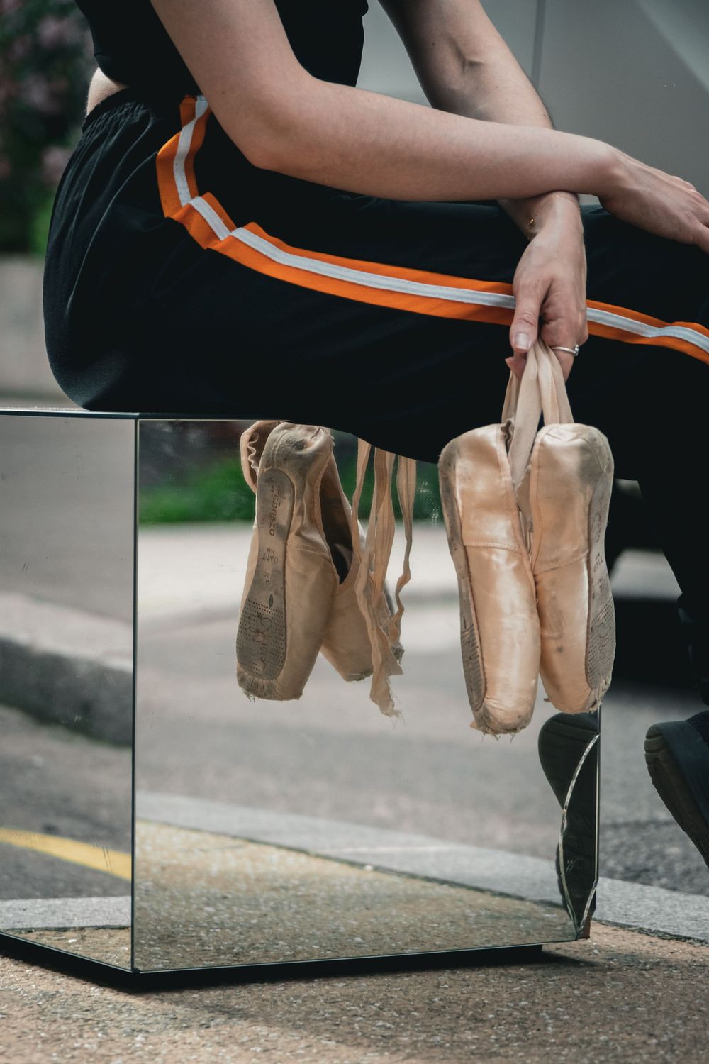 Chaussons de danse classique suspendus devant un miroir, reflétant les jambes de la danseuse.