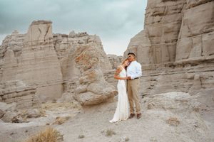 Romantic couple embracing in a dramatic desert canyon landscape with towering sandstone rock formations.