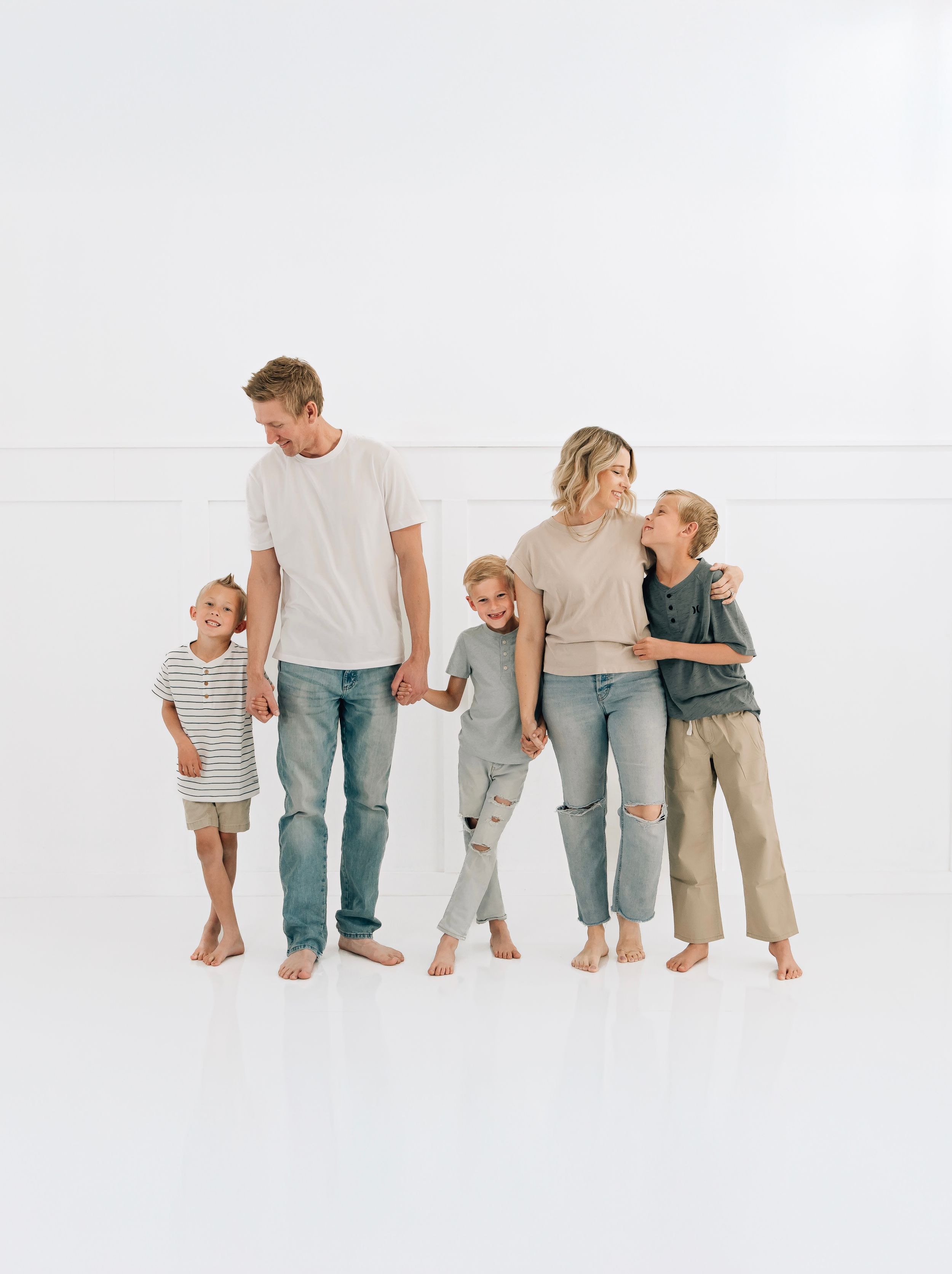Family smiling together during a studio photography session in Peoria, Arizona. wearing casual neutral tones and denim.