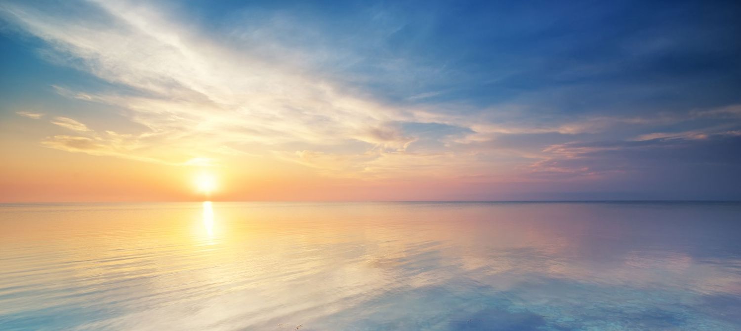 Woman in flowing white tulle gown poses gracefully against a serene blue sky backdrop.