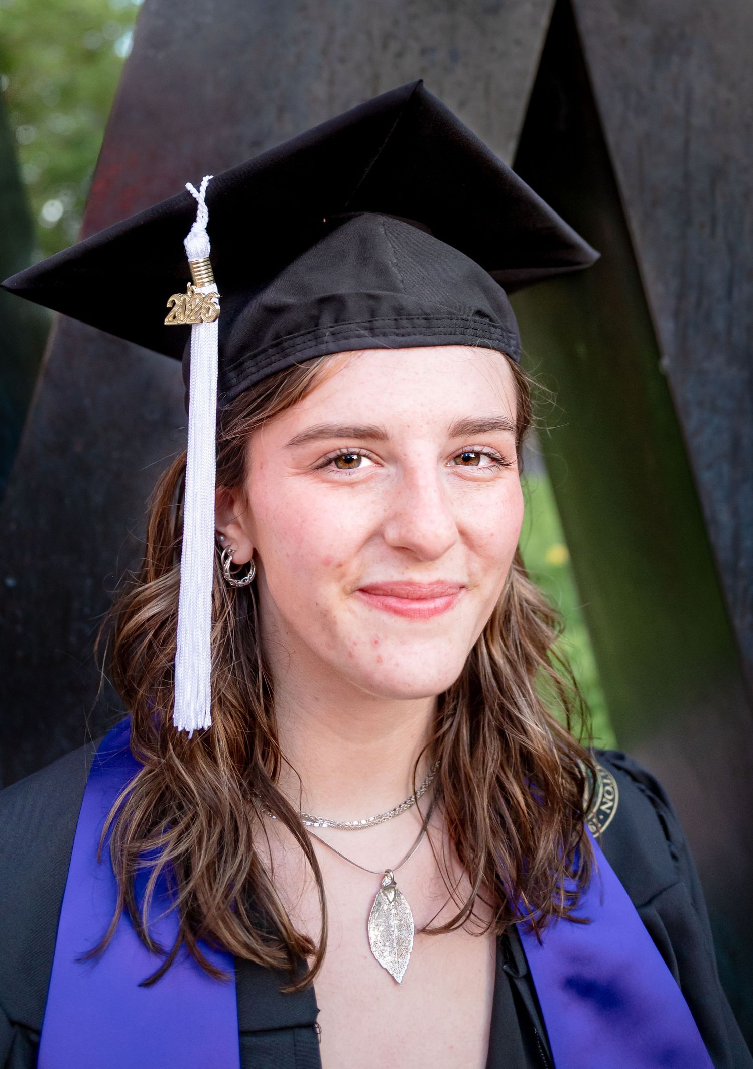 UW graduate posing beside the iconic W Sculpture during commencement season