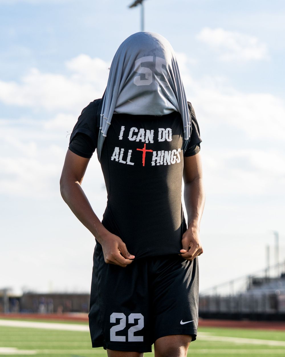 Soccer player number 22 lifting jersey to reveal motivational shirt reading I Can Do All Things with cross.