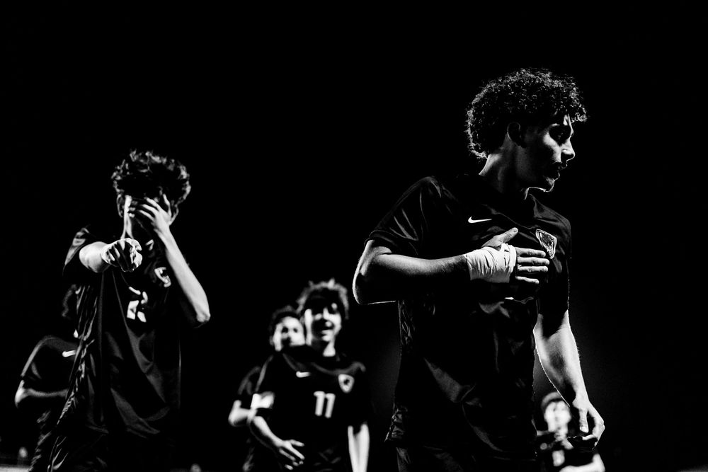 Dramatic black and white photo of soccer players walking off field after night game.