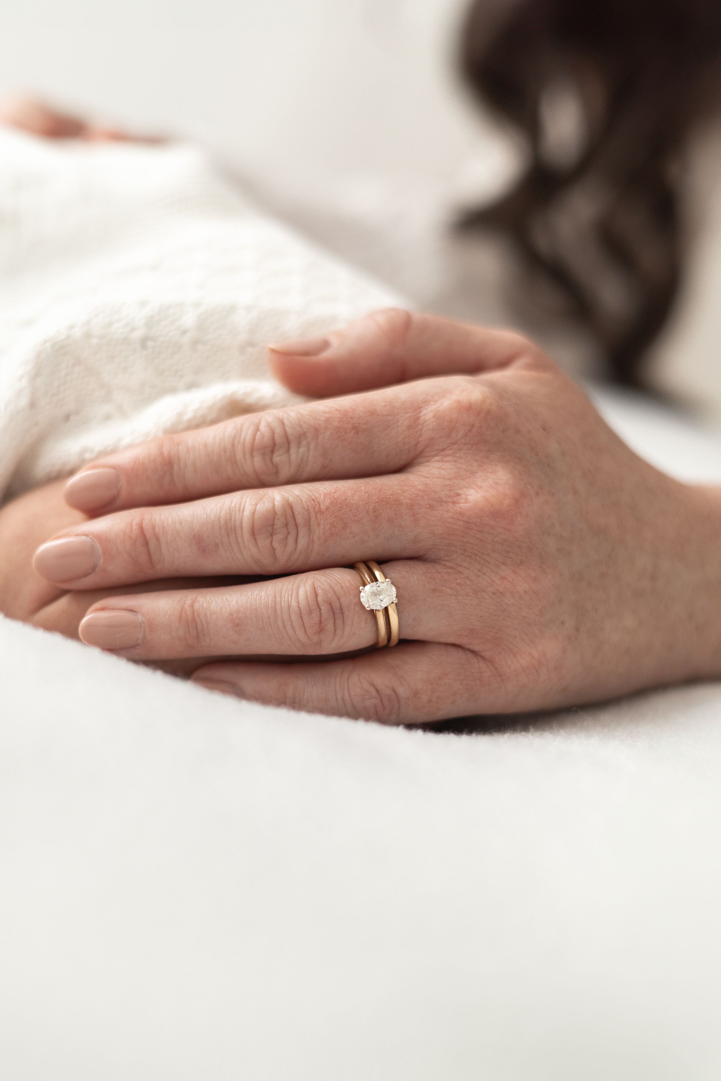 Close-up of mums hand wearing a gold engagement ring while cradling their newborn baby Nottingham newborn photographer