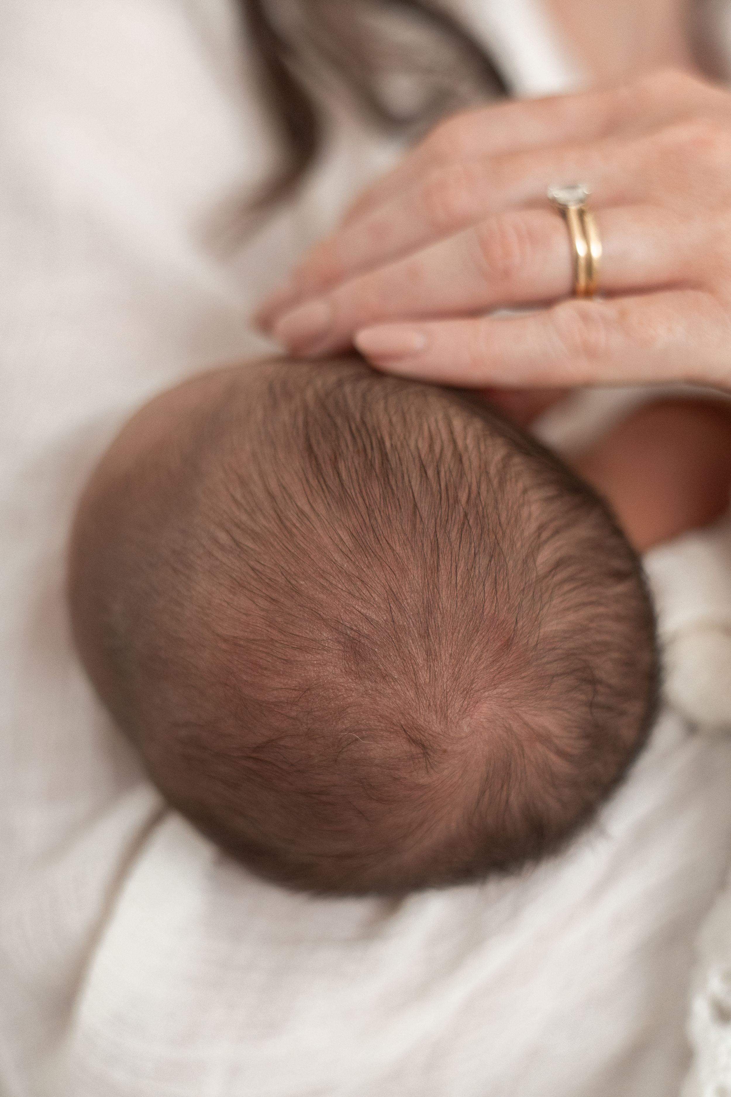 Close-up of a newborn baby's head resting against a mother's chest Nottingham newborn photographer