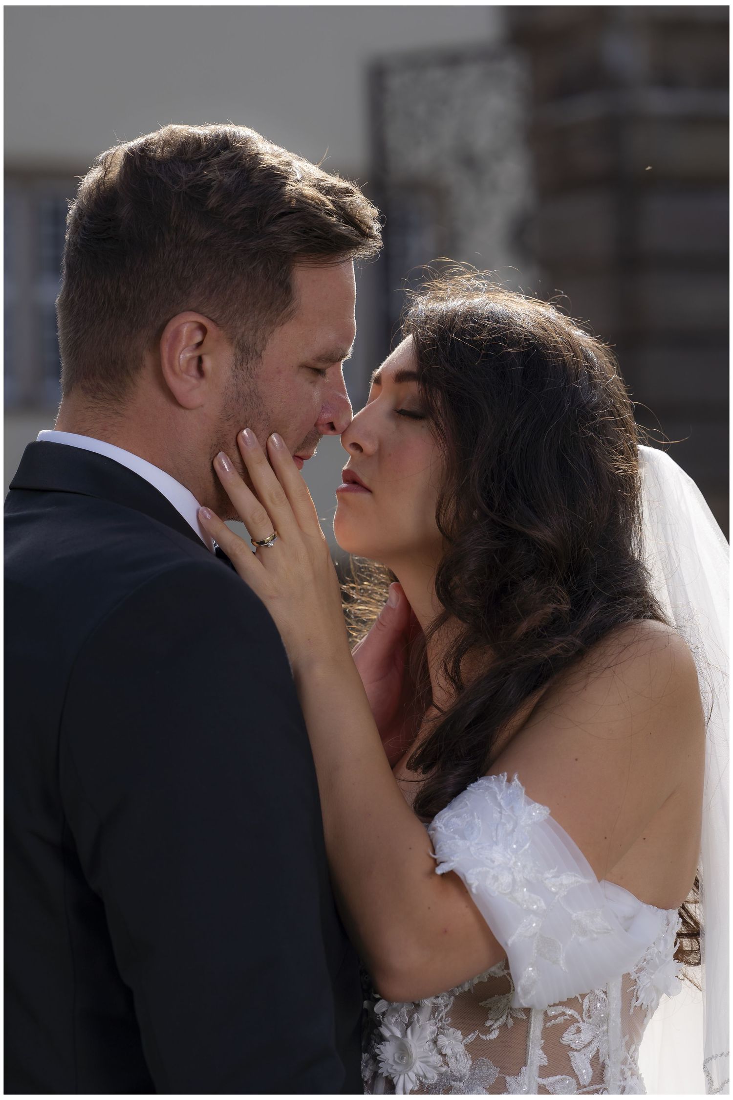 Bride and groom sharing intimate romantic kiss moment on sunny wedding day.
