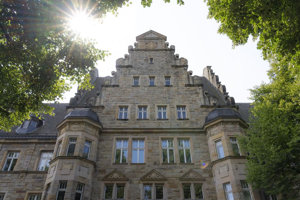 Historisches Steingebäude mit gestufter Giebelarchitektur, von unten vor sonnigem Himmel fotografiert. Altes Amtshaus Bochum