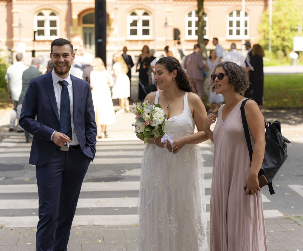 Eine formelle Versammlung im Freien mit Teilnehmern in eleganter Kleidung in der Nähe eines historischen Gebäudes.